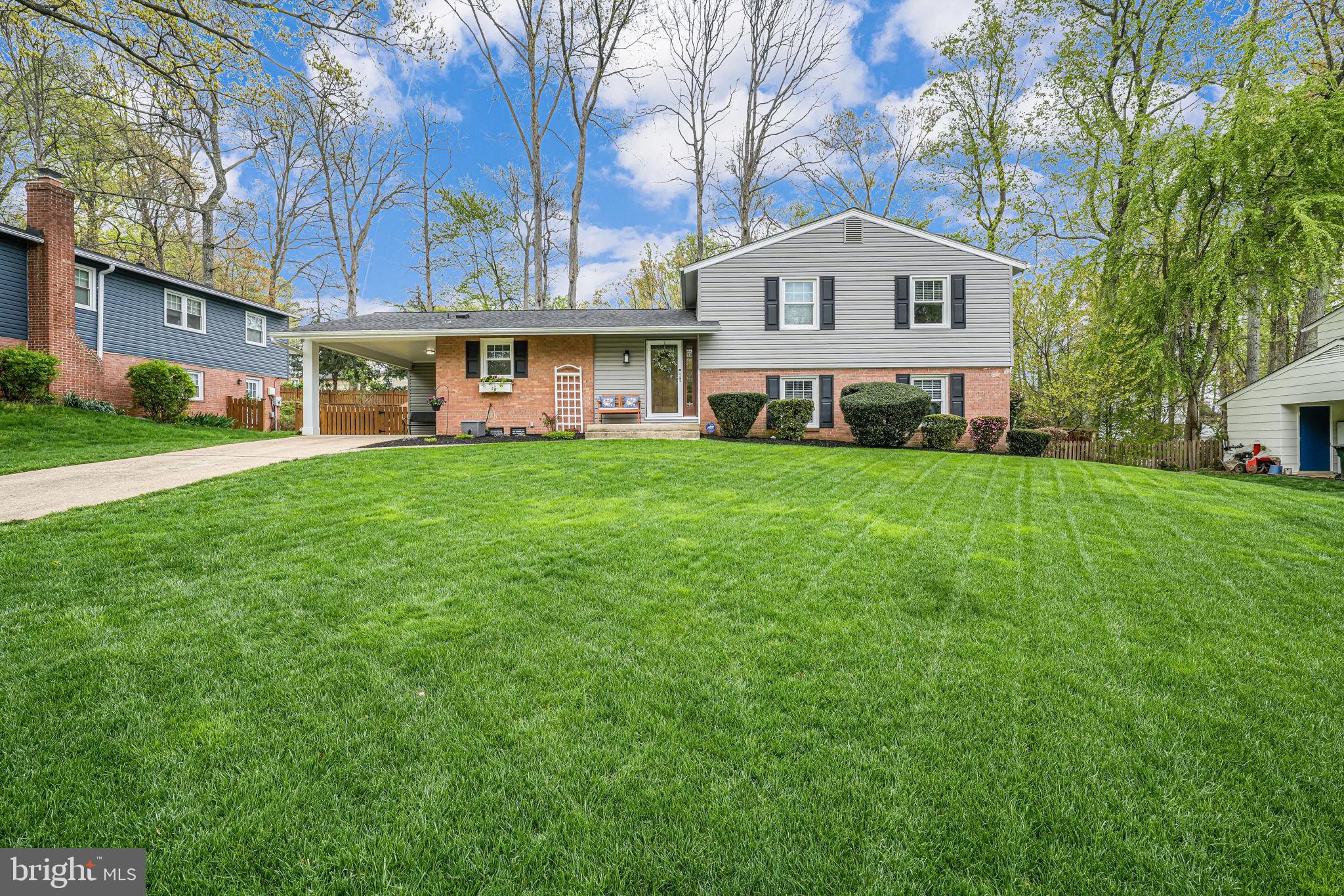 a view of white house with a big yard and large trees