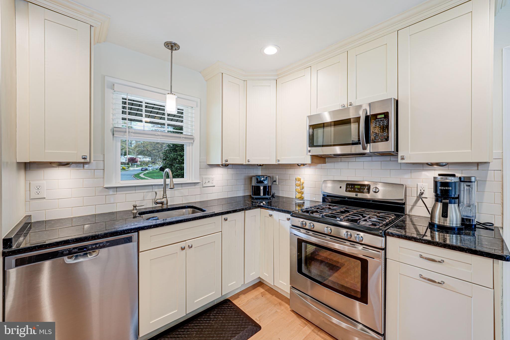 8315 Greeley Boulevard Springfield, VA 22152 - Photo 4 of 44 a kitchen with stainless steel appliances granite countertop a sink a stove a microwave and wooden cabinets
