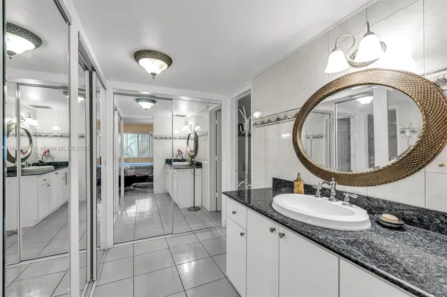 a bathroom with a granite countertop sink a mirror and shower