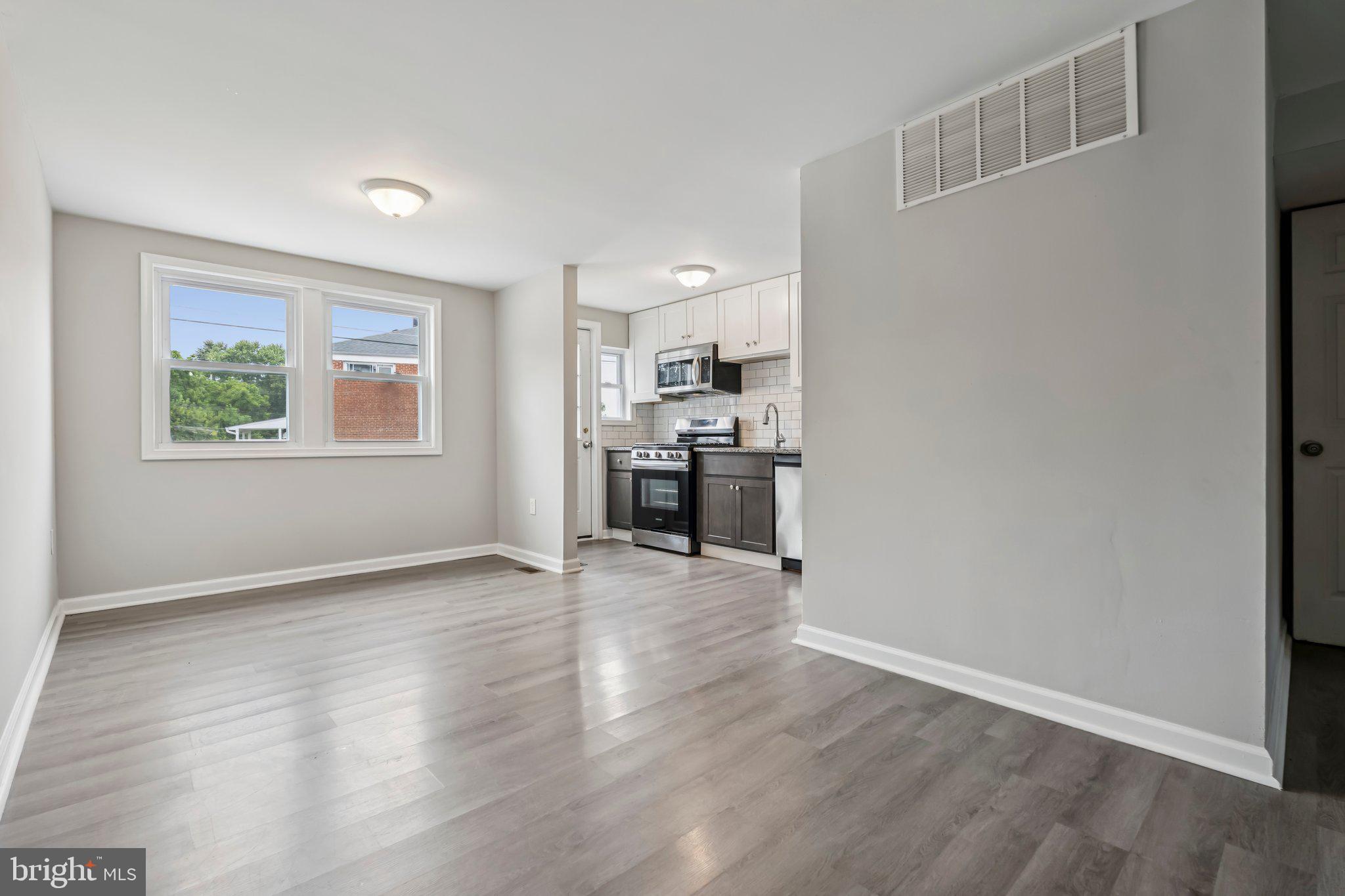7838 St Boniface Lane Dundalk, MD 21222 - Photo 6 of 37 an empty room with wooden floor kitchen view and windows