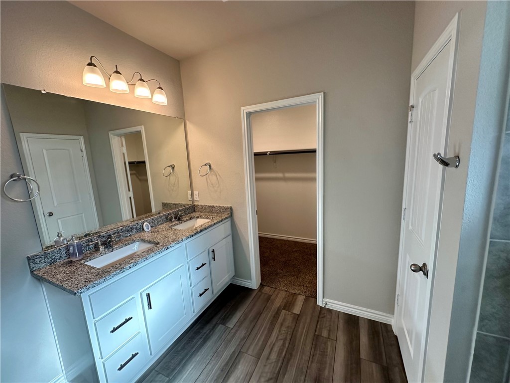 2110 Chief Street Bryan, TX 77807 - Photo 7 of 16 Bathroom featuring a walk in closet, double vanity, and dark wood-type flooring