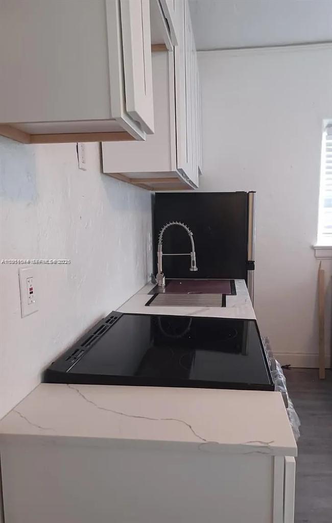 2822 Pine Tree Drive, Unit 4A Miami Beach, FL 33140 - Photo 2 of 13 a kitchen with a stove and white cabinets