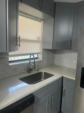 a view with a sink a counter space and cabinets
