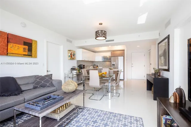 a living room with furniture kitchen view and a large window