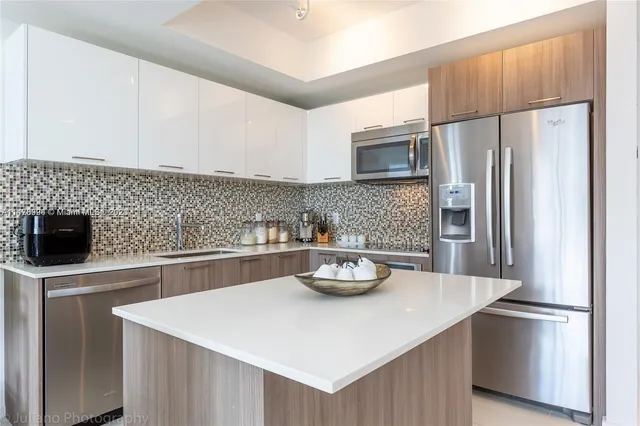 a kitchen with stainless steel appliances granite countertop a refrigerator a sink a stove a dining table and chairs