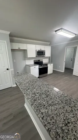 a view of a kitchen with kitchen island a sink wooden floor and glass door