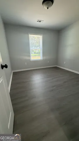 en empty room with wooden floor and windows