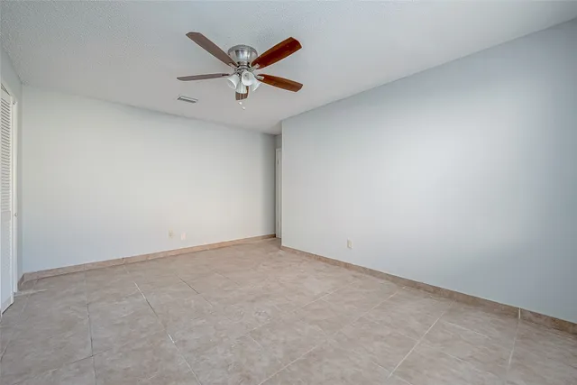 an empty room with ceiling fan and window