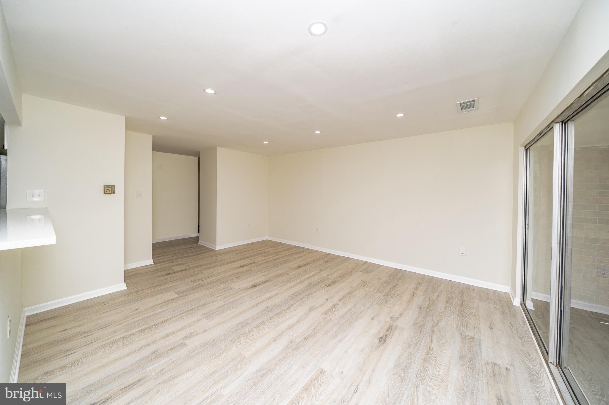 9910 Walker House Road, Unit 99104 Gaithersburg, MD 20886 - Photo 7 of 32 a view of an empty room with wooden floor and a window