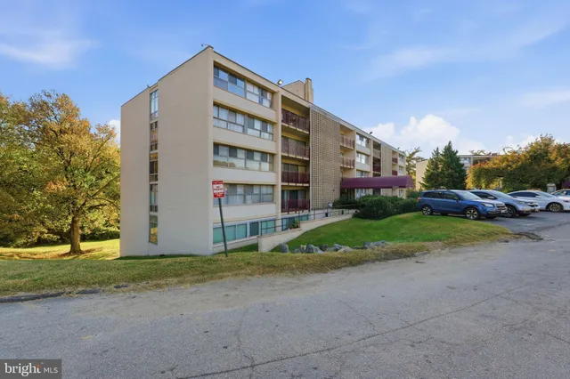 a front view of a building with cars parked