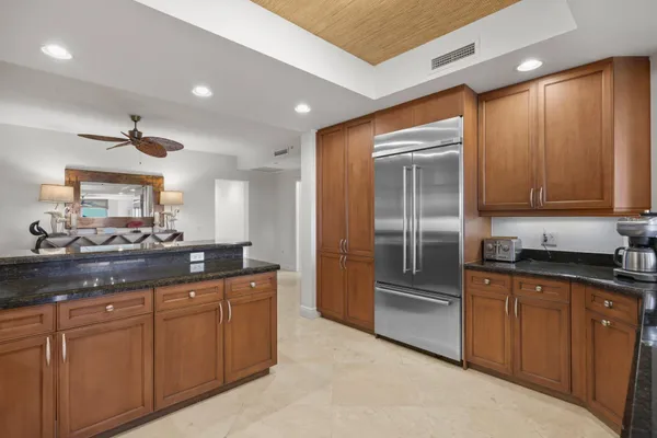 a kitchen with granite countertop a refrigerator and cabinets