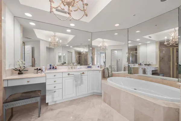 a large white bathroom with a large tub sink vanity and a large mirror
