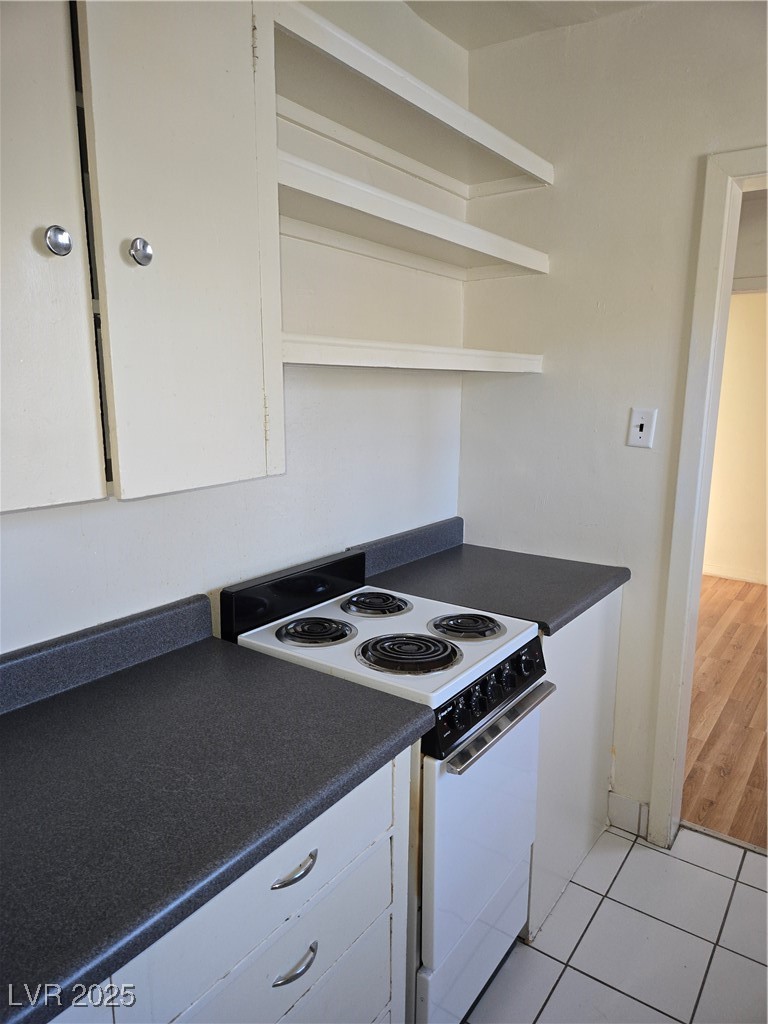 633 Nevada Way, Unit 3 Boulder City, NV 89005 - Photo 4 of 7 Kitchen featuring dark countertops, white cabinetry, and light tile patterned flooring