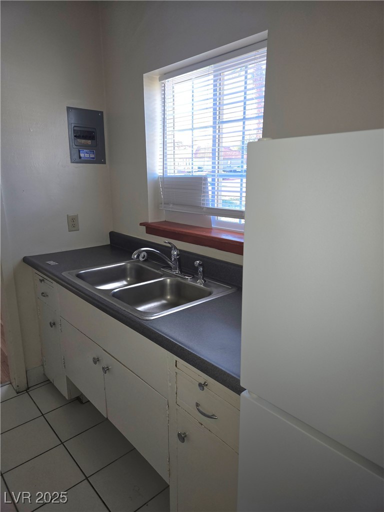 633 Nevada Way, Unit 3 Boulder City, NV 89005 - Photo 5 of 7 Kitchen with freestanding refrigerator, dark countertops, white cabinets, electric panel, and light tile patterned floors