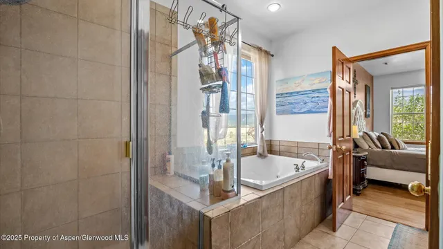 a bathroom with a tub a sink and a large mirror next to a window
