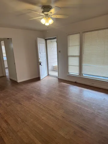 a view of empty room with wooden floor and fan