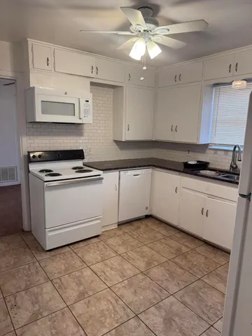 a kitchen with granite countertop a stove a sink and a refrigerator