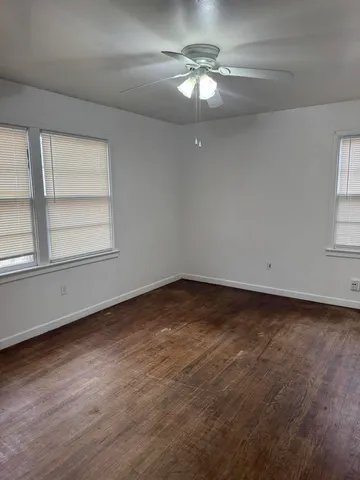 an empty room with a chandelier fan and windows