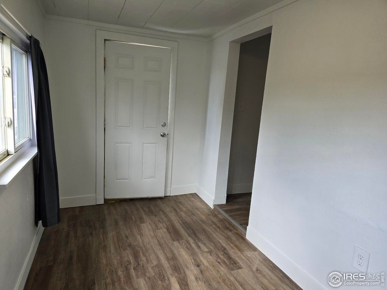 1324 7th Avenue Greeley, CO 80631 - Photo 3 of 22 a view of an empty room with wooden floor and a window