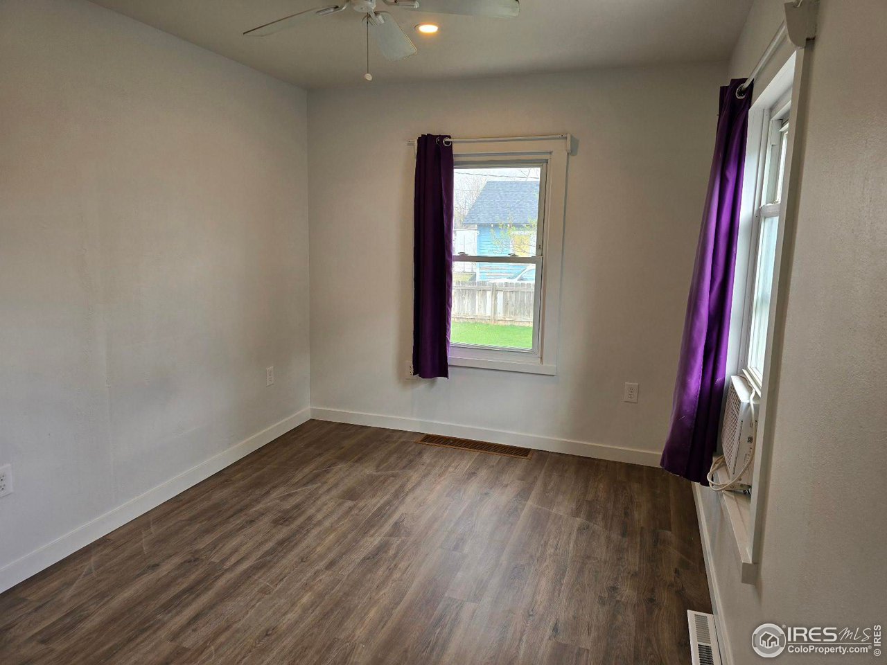 1324 7th Avenue Greeley, CO 80631 - Photo 7 of 22 an empty room with wooden floor and windows