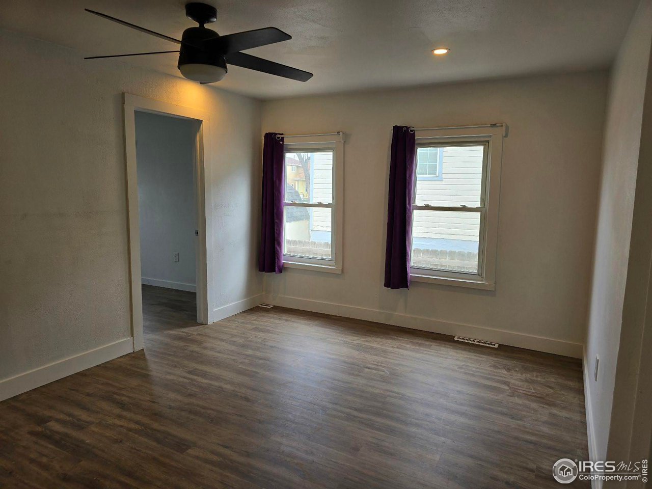 1324 7th Avenue Greeley, CO 80631 - Photo 10 of 22 an empty room with wooden floor and windows