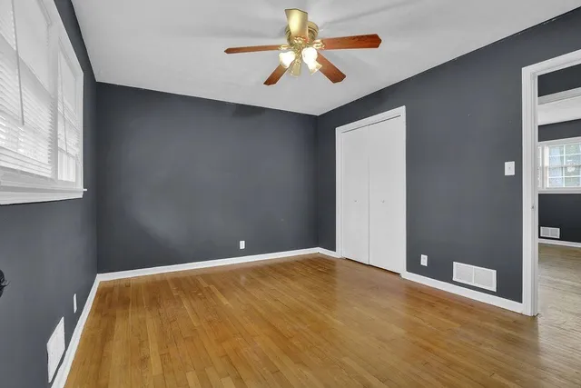 a view of a big room with wooden floor and a chandelier fan