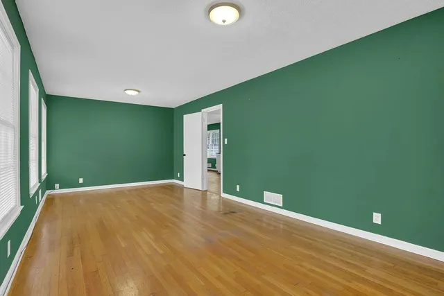 a view of a big room with wooden floor and windows