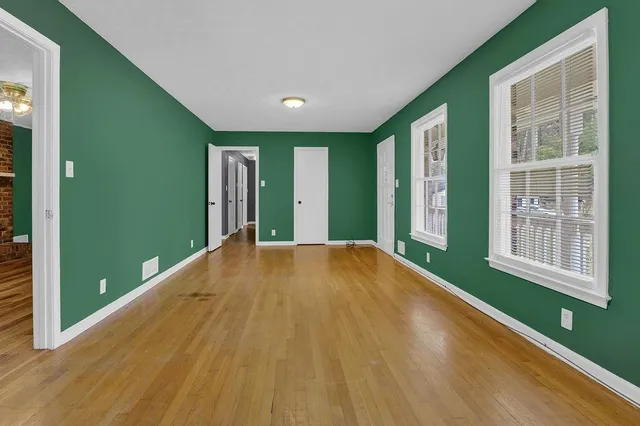 a view of an empty room with a window and wooden floor