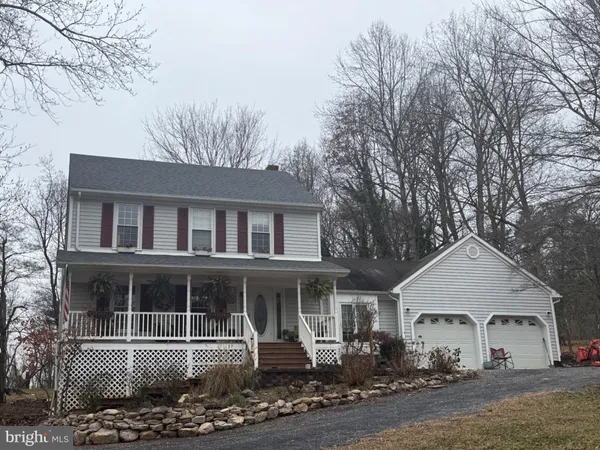 a front view of a house with yard and trees in the background