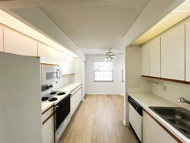 a kitchen with granite countertop a sink wooden floor and stainless steel appliances