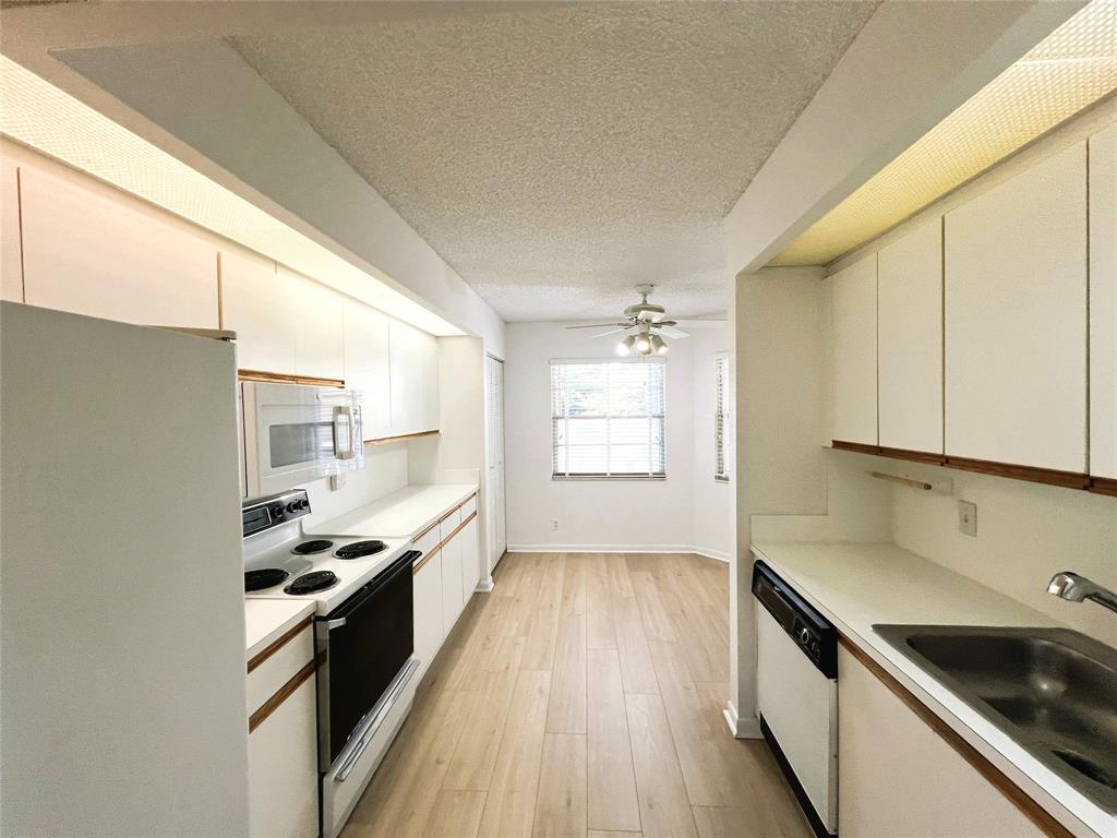 1803 Eleuthera Point, Unit J2 Coconut Creek, FL 33066 - Photo 16 of 27 a kitchen with granite countertop a sink wooden floor and stainless steel appliances