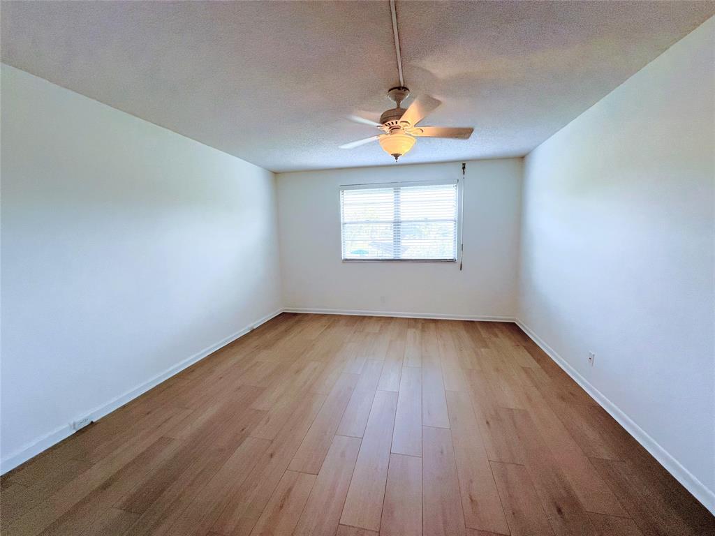 1803 Eleuthera Point, Unit J2 Coconut Creek, FL 33066 - Photo 7 of 27 an empty room with window and wooden floor