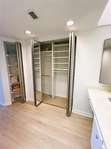 a view of an empty room with wooden floor and a kitchen