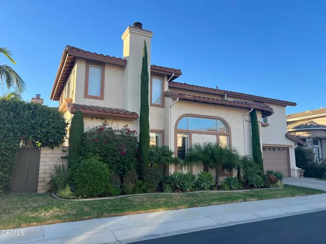 a front view of a house with a yard and potted plants