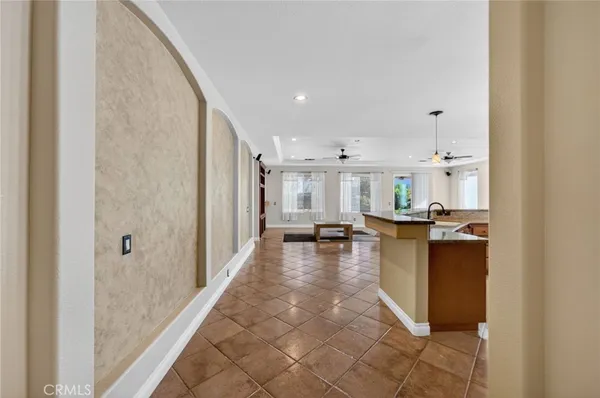 a living room with stainless steel appliances furniture a rug and a kitchen view