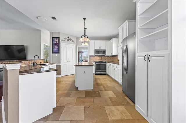 a kitchen with kitchen island a sink a counter top space appliances and cabinets