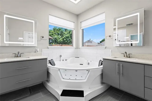 a bathroom with a double vanity sink mirror and bathtub