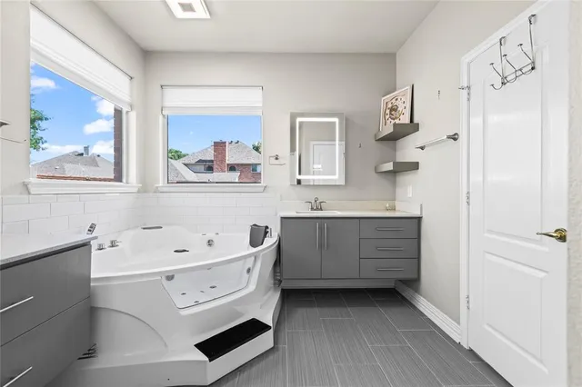 a bathroom with a double vanity sink a mirror a window and a bathtub