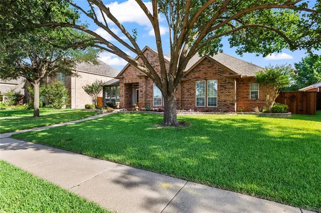 a front view of a house with a garden and trees