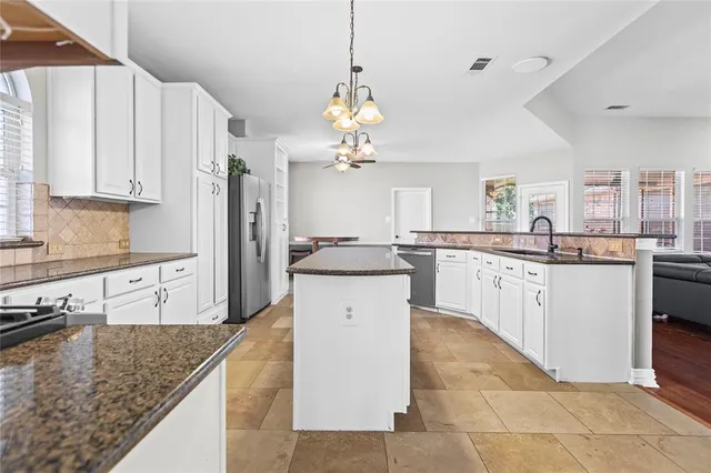 a kitchen with kitchen island granite countertop a sink a counter top space appliances and cabinets