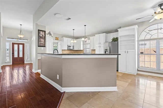 a kitchen with stainless steel appliances granite countertop a refrigerator a sink dishwasher a stove and a wooden cabinets with wooden floor