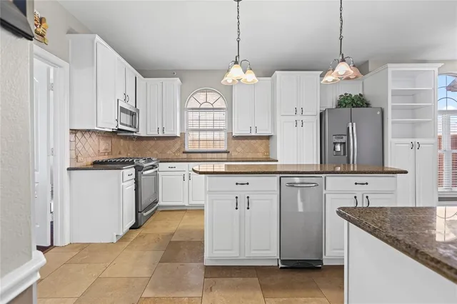 a kitchen with kitchen island granite countertop a sink a counter space appliances and cabinets