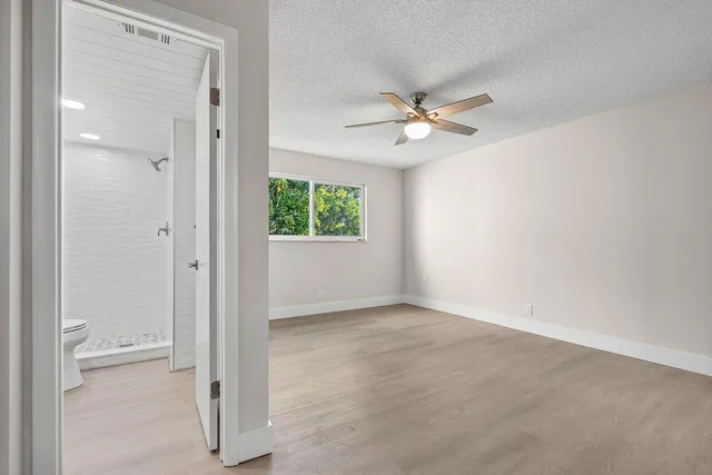 an empty room with a ceiling fan and a window