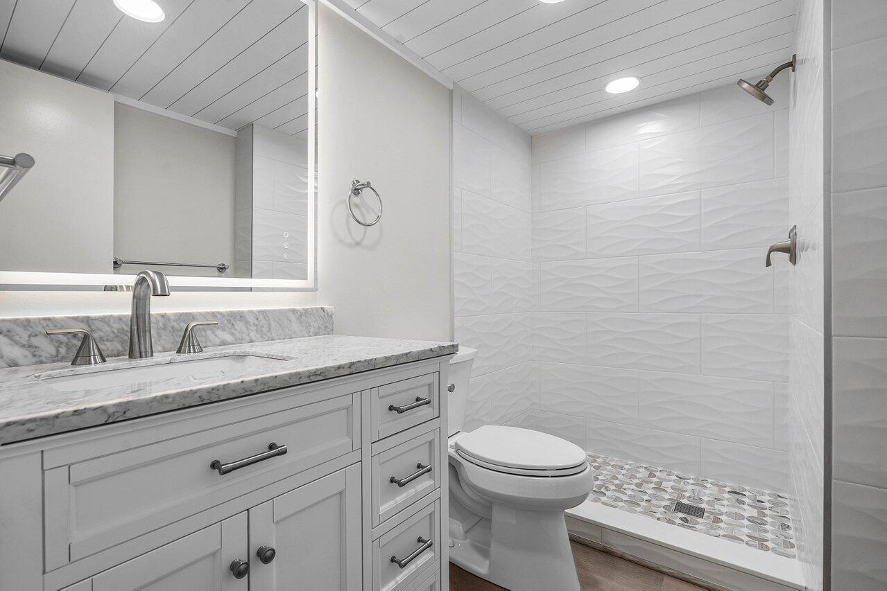 2601 Northeast 3rd Street, Unit 3040 Boynton Beach, FL 33435 - Photo 19 of 24 a bathroom with a granite countertop toilet a sink a mirror and shower