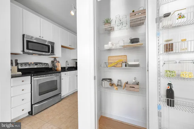 a kitchen with stainless steel appliances granite countertop white cabinets a microwave and a refrigerator