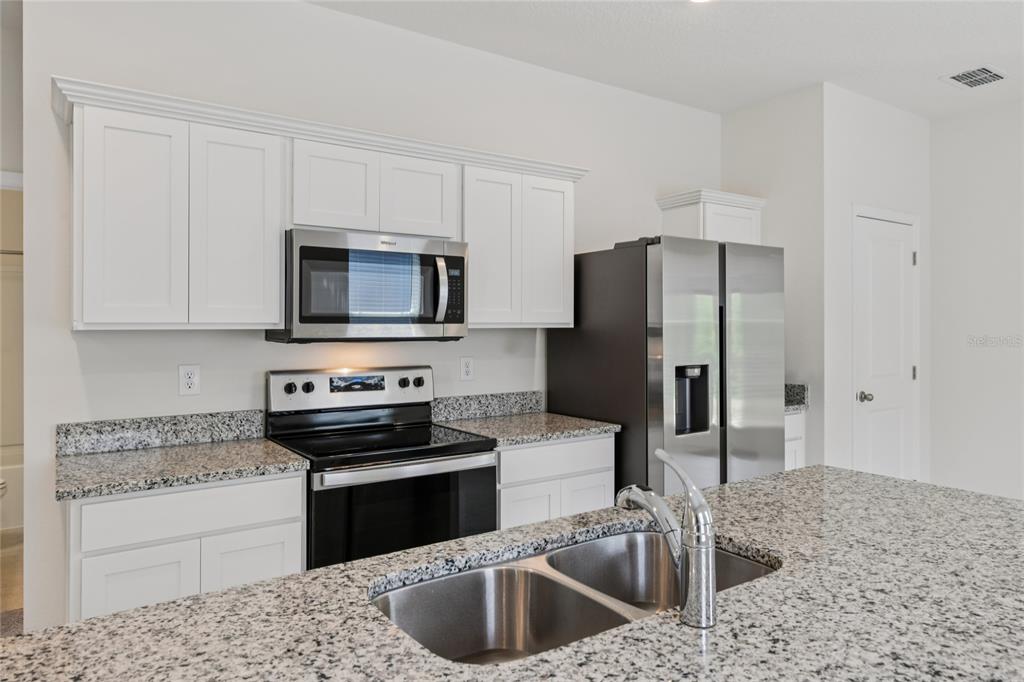 2352 Litchfield Loop DeLand, FL 32720 - Photo 8 of 24 a kitchen with stainless steel appliances granite countertop a sink stove and refrigerator