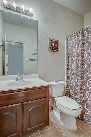 a bathroom with a granite countertop toilet sink and mirror