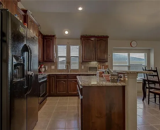a kitchen with stainless steel appliances granite countertop a sink refrigerator and cabinets