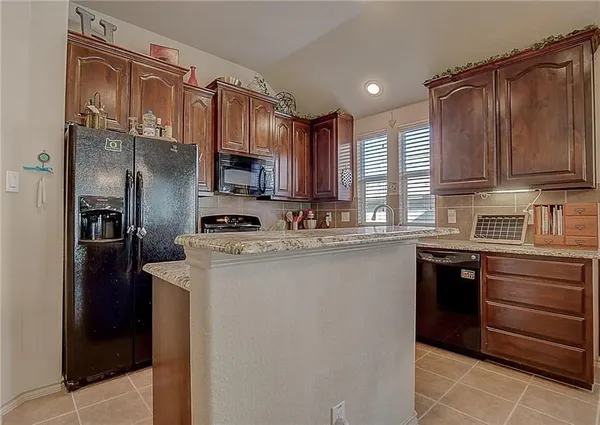 a kitchen with stainless steel appliances granite countertop a refrigerator a stove a sink and a microwave