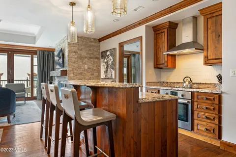 a kitchen with stainless steel appliances granite countertop a stove a sink dishwasher a dining table and chairs with wooden floor